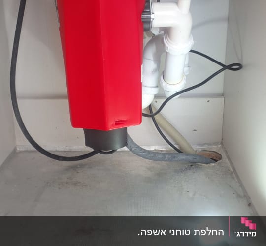 מתקן אדום מתחת לכיור עם צינורות חיבור